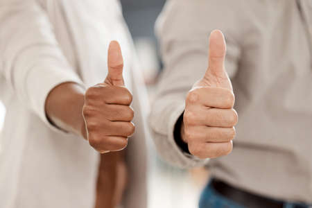 Never give up on a dream. two unrecognizable call centre agents showing thumbs up in an office.