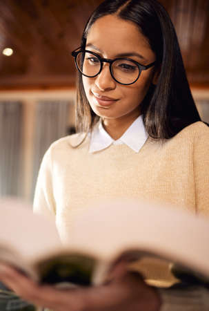 Everything you learn will help you in your future. a female student wearing glasses while reading at home.の写真素材