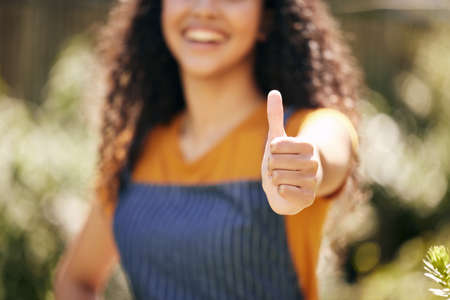 Can you tell what colour my thumb is. an unrecognizable female florist showing a thumbs up at a nursery.の写真素材