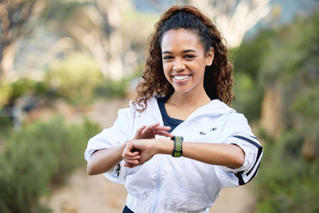 Besting my own best time. a young woman checking her running time on her smart watch.の写真素材