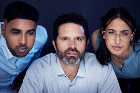 Taking a closer look at the details. a group of businesspeople working on a computer in an office at night.の写真素材