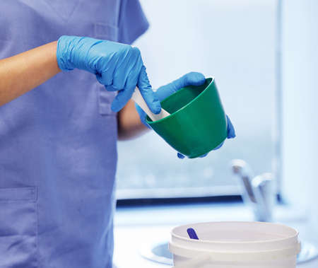 The makings of a dental mould. an unrecognisable dentist preparing plaster to make a mould during a...