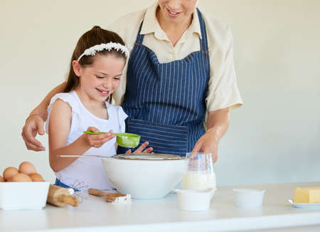 Shes a natural cook. a little girl helping her parent cook in the kitchen at home.