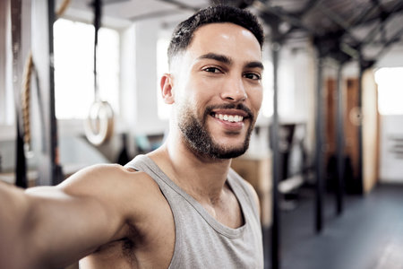 Our greatest glory is not in never failing. a young man taking a selfie in a gym.の写真素材