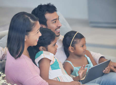 Teaching the little ones the way of the world. a young family relaxing together while using a digital tablet.の写真素材