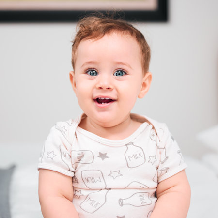Isnt he the cutest. an adorable baby boy sitting on a bed.