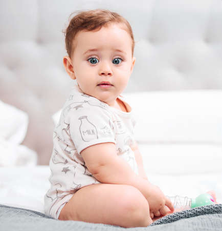 Hes the most adorable baby youve seen today. an adorable baby boy sitting on a bed.の写真素材