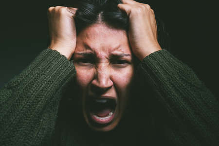 Is it all in your head. Studio shot of a young woman experiencing mental anguish and screaming...