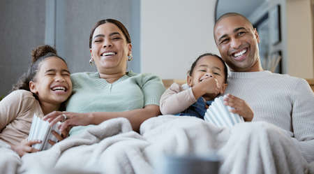 Arms for me to hold them. a happy family eating popcorn while watching television together at home.の写真素材