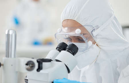 Carrying out routine tasks as accurately as possible. a scientist wearing a radiation suit while...