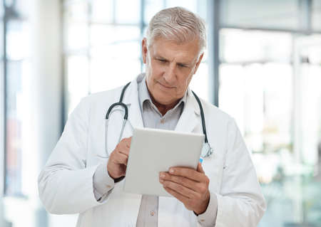 Rejoice in your work. a doctor using a tablet in a hospital.の写真素材