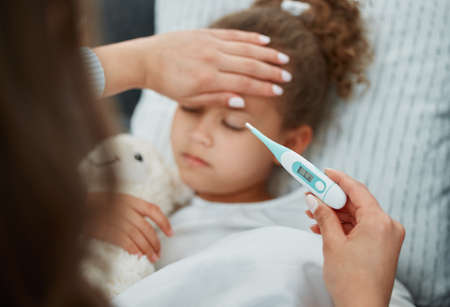 Little children being sick is heartbreaking. a mother taking her daughters temperature.