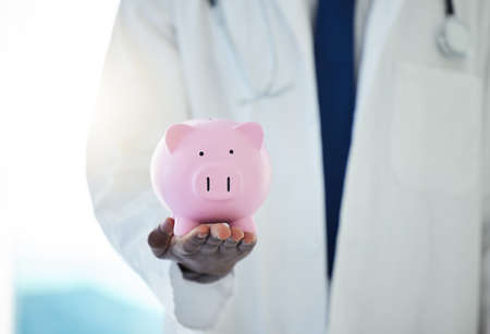 Protect your health at all costs. an unrecognisable doctor holding a piggybank.の写真素材