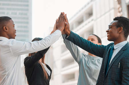 High five for a job well done. a group of businesspeople giving each other a high five in the city.