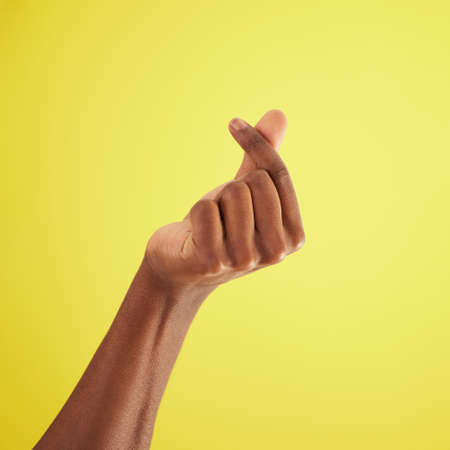 Ka ching. Studio shot of an unrecognisable man rubbing his fingers together against a yellow...