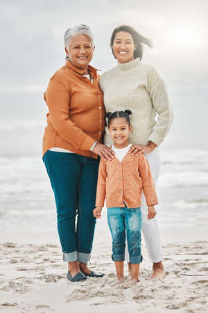 The beach is great for any generation. Full length shot of an attractive young woman on the beach with her mother and daughter.の写真素材