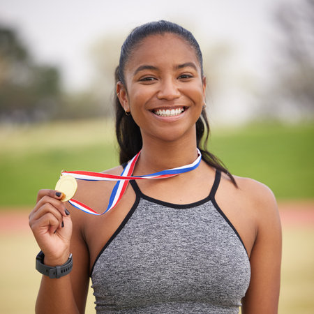 Bringing home the gold. Cropped portrait of an attractive young female athlete celebrating her...