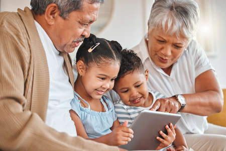 Blessed to be loved. grandparents bonding with their grandchildren and using a digital tablet on a...