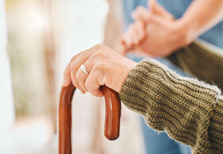 Wouldnt be able to walk without it. an elderly woman using a walking cane with the help of her nurse.の写真素材
