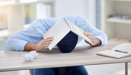 The device of my misery. a businessman covering his head with his laptop.