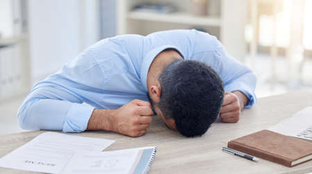 The walls are closing in on me. a businessman taking a nap due to being overworked.