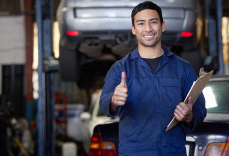 Youve passed. Cropped portrait of a handsome young male mechanic giving thumbs up towards the camera while in his workshop.の写真素材