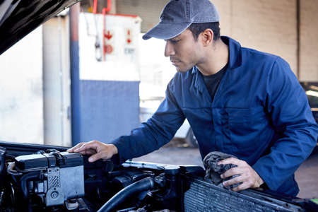 Might need a new battery. a handsome young male mechanic working on the engine of a car during a...