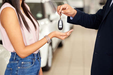 Its all yours now. a car salesman handing car keys over to a young woman.
