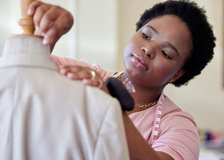 Making some minor adjustments. an attractive young seamstress fitting a suit onto a mannequin in her boutique.の写真素材