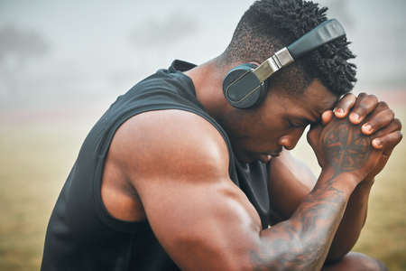 Take a moment to gain your focus again. a muscular young man wearing headphones while exercising...