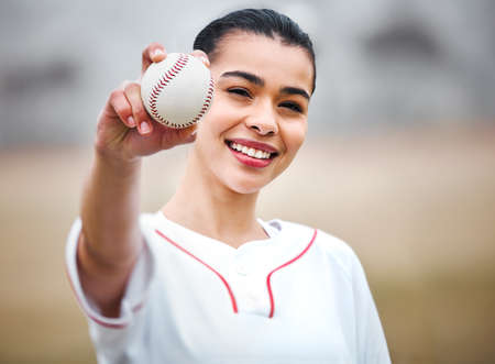 Time for a curve ball. Cropped portrait of an attractive young female baseball player standing outside.の写真素材