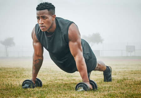 Stay on the rise. a muscular young man exercising with dumbbells outdoors.の写真素材
