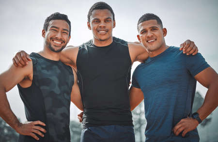 Were brining it home. Cropped portrait of three handsome young male athletes standing together on an outdoor running track.の写真素材