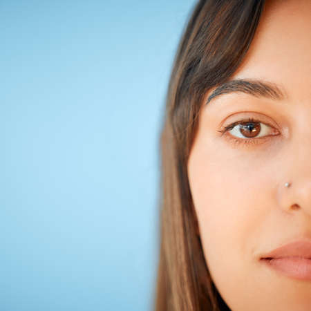 Simply lovely. Closeup portrait of a beautiful young woman against a blue background.の写真素材