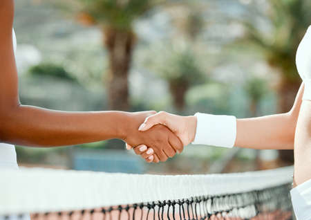 May the best player win. two sporty women shaking hands while playing tennis together on a court.の写真素材