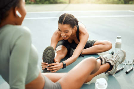 They always start with the warmup. two attractive young female athletes warming up outside before...