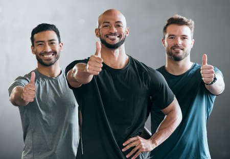 Youve got our support. Cropped portrait of three handsome young male athletes giving thumbs up towards the camera against a grey background.の写真素材