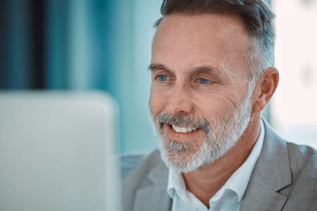 Keep your face always toward the sunshine. a mature man using a computer at work in a office.
