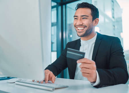 Success is the result of the quality. a businessman using a computer and credit card at work.の写真素材
