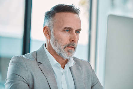 Keep on going. a mature man using a computer at work in a office.
