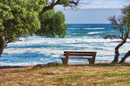 Relaxing bench with sea or ocean view to enjoy calm, peaceful or zen beach with waves washing on...