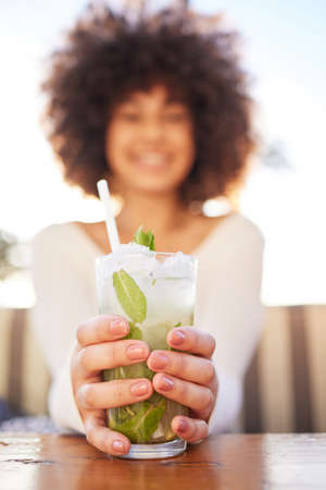Youve gotta taste this. Portrait of a beautiful young woman having a drink at a bra outside.の写真素材