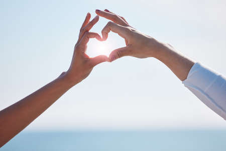 Where there is love, there is light. Closeup shot of two unrecognisable women making a heart shape with their fingers outdoors.の写真素材