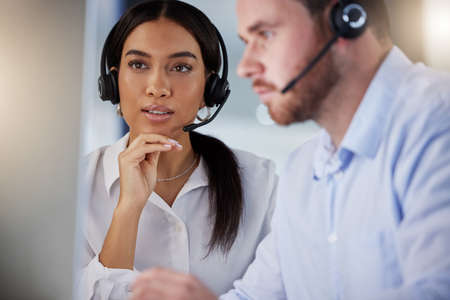 Lets troubleshoot this together. two call centre agents working together on a computer in an office...