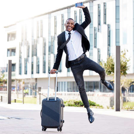 I couldnt ask for more. a young businessman jumping for joy while holding his smartphone.の写真素材