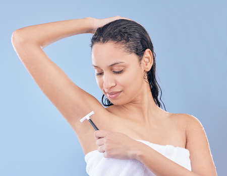 Did you know that shaving your armpits results in less sweating. a young woman using a disposable razor to shave her underarms.の写真素材