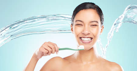 Its very difficult for some people to practice good hygiene. a young woman brushing her teeth against a studio background.の写真素材