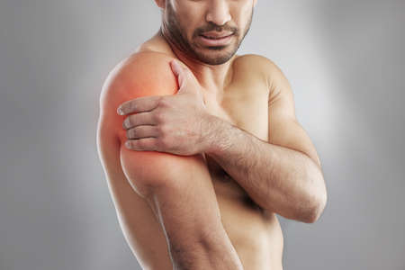 Without pain, without sacrifice, wed have nothing. Cropped studio shot of a muscular young man experiencing shoulder pain against a grey background.の写真素材