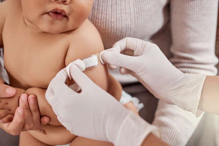A few days and youll feel better. a doctor applying a plaster on a babys arm.