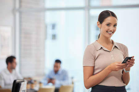 Another day at the helm. a young businesswoman using her smartphone to send a text message.